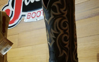 Black leather cowboy boots by Justin with intricate stitching and a classic design, ideal for western wear enthusiasts.