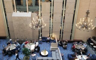 Aerial view of a dining area featuring guests at tables, chandeliers, and modern furnishings in a spacious setting.